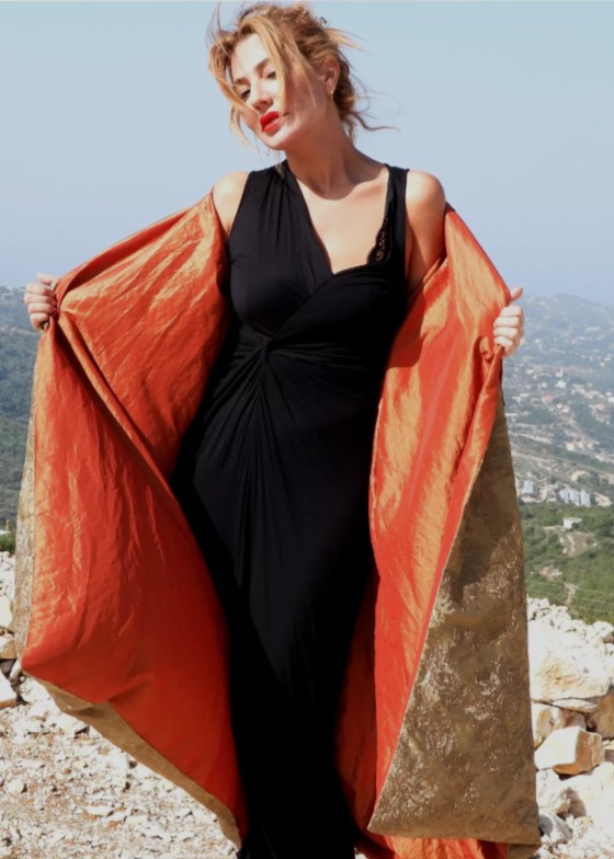 Roula Harb — Gold Brocade Robe, holding it open over the hills